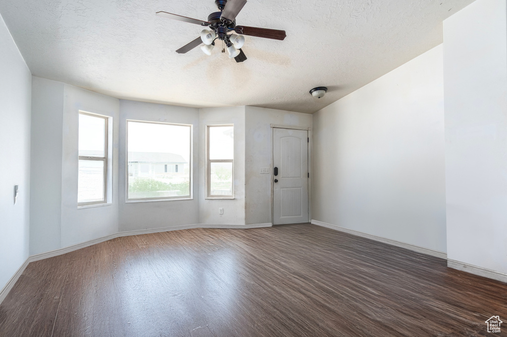 Spare room with wood finished floors, a textured ceiling, a ceiling fan, and baseboards