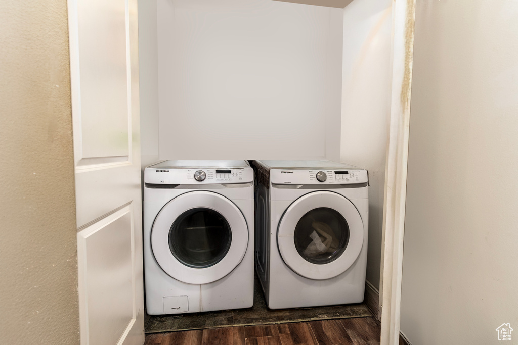 Clothes washing area with independent washer and dryer and dark wood finished floors