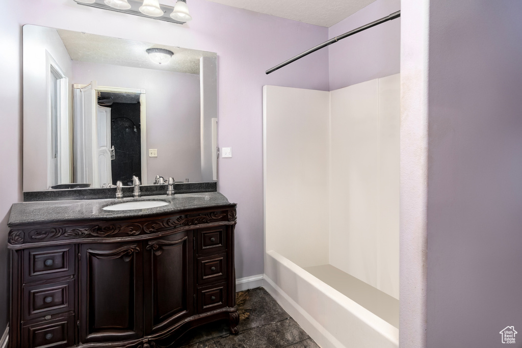Full bath with vanity, baseboards, and shower / bath combination