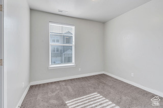 Carpeted spare room featuring baseboards