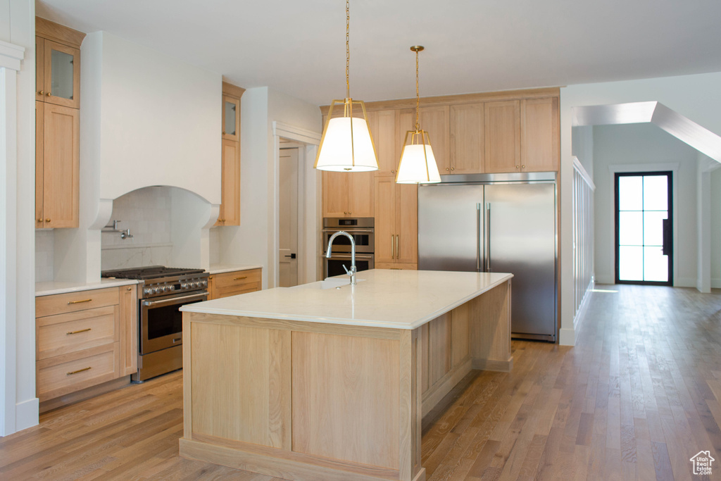 Kitchen with premium appliances, light brown cabinets, light wood finished floors, and light countertops
