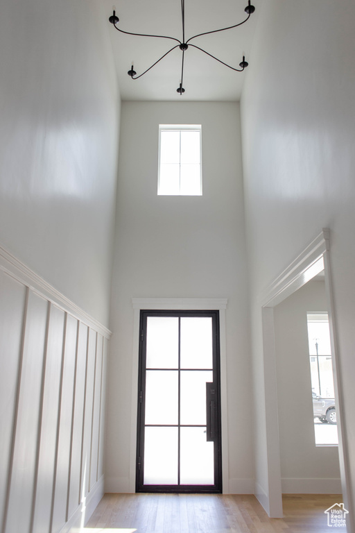 Entryway with a high ceiling, a chandelier, light wood-style flooring, and baseboards