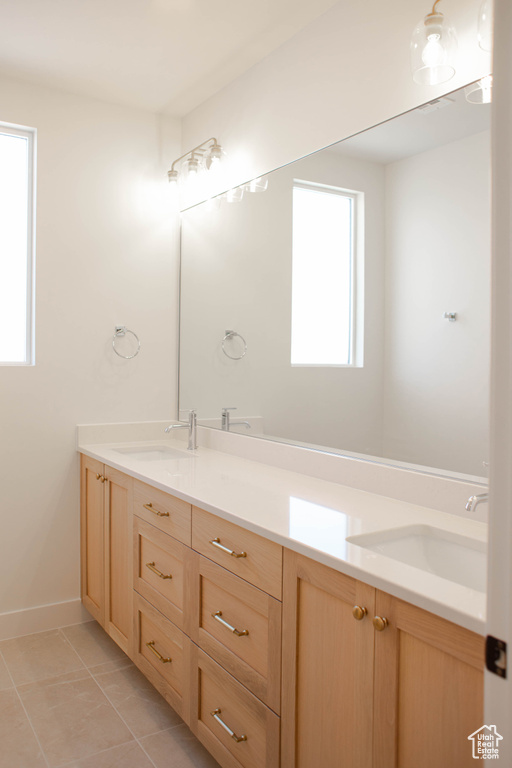 Full bathroom with double vanity, baseboards, and tile patterned floors