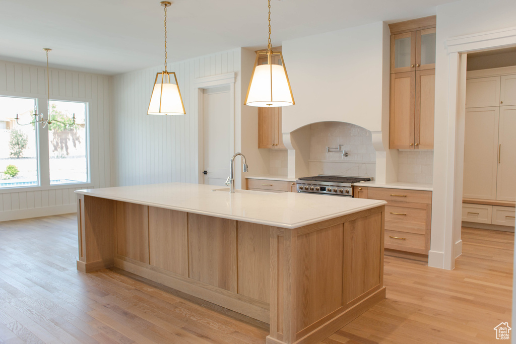 Kitchen with light wood finished floors, a sink, stove, and decorative backsplash