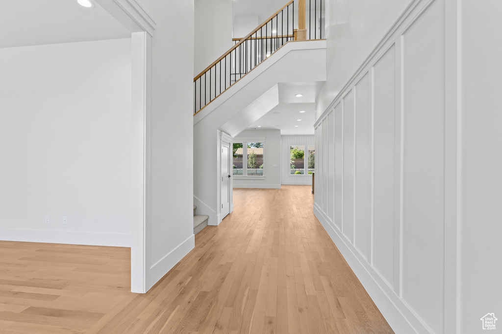 Foyer entrance featuring stairs, light wood-type flooring, recessed lighting, baseboards, and a high ceiling