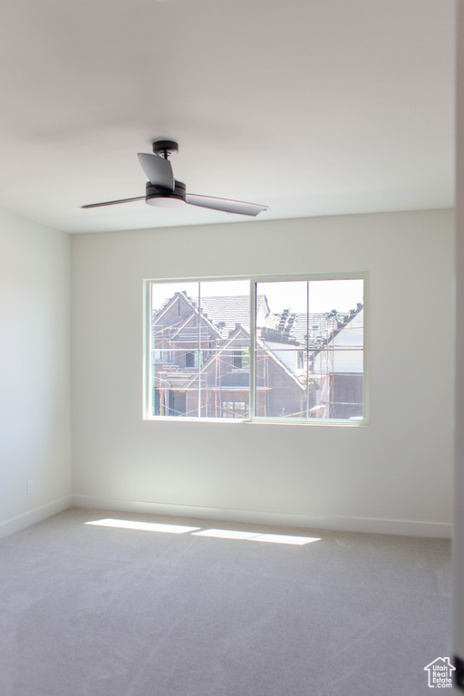 Carpeted empty room with a ceiling fan and baseboards