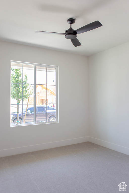 Empty room with light carpet, baseboards, and a ceiling fan