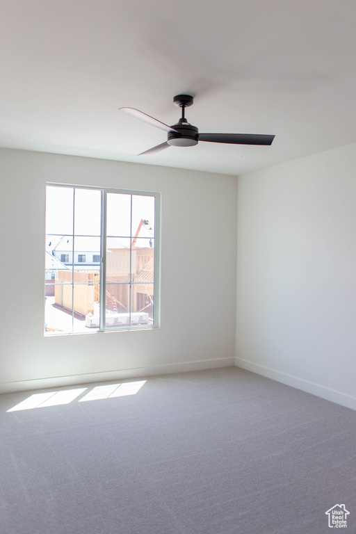 Carpeted empty room with a ceiling fan and baseboards