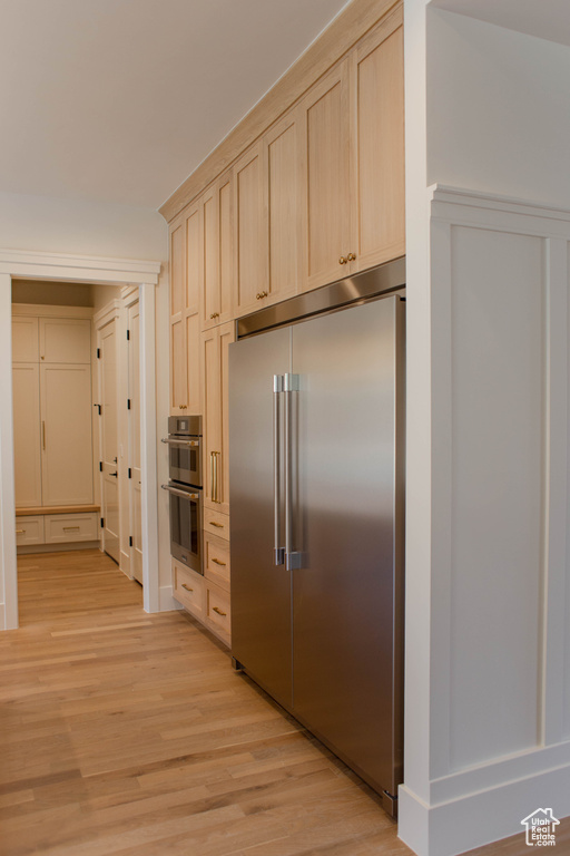 Kitchen with stainless steel appliances, light wood-style flooring, and light brown cabinets