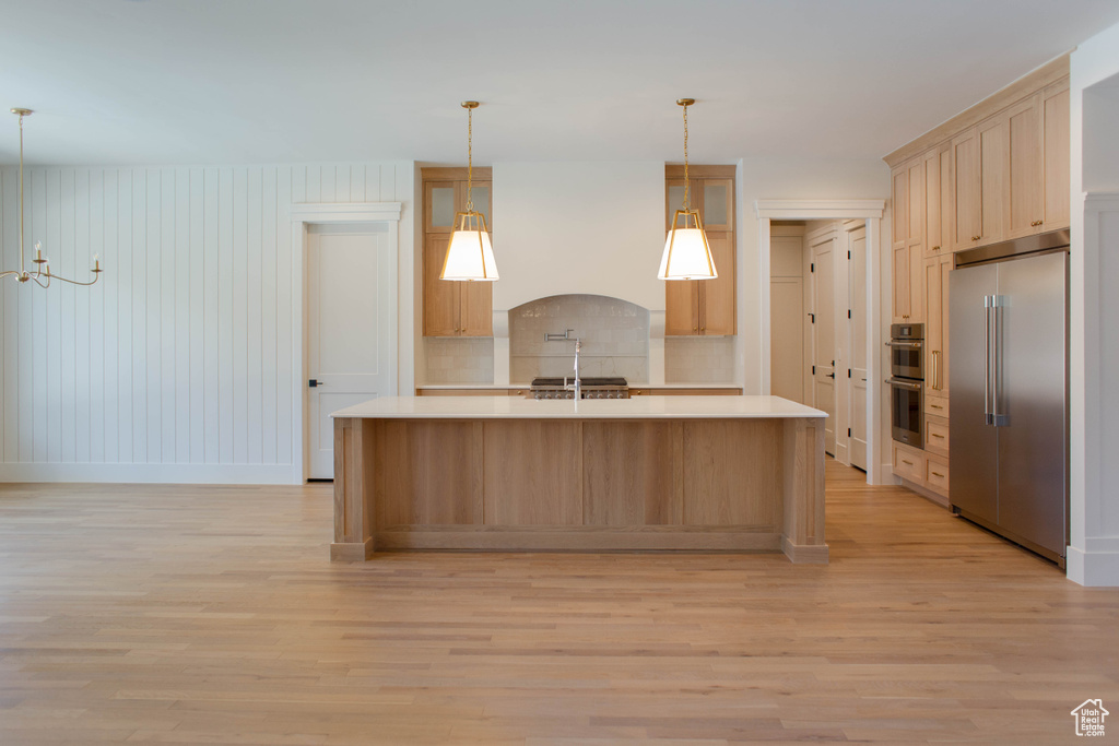 Kitchen with stainless steel appliances, light wood-style floors, light countertops, and tasteful backsplash