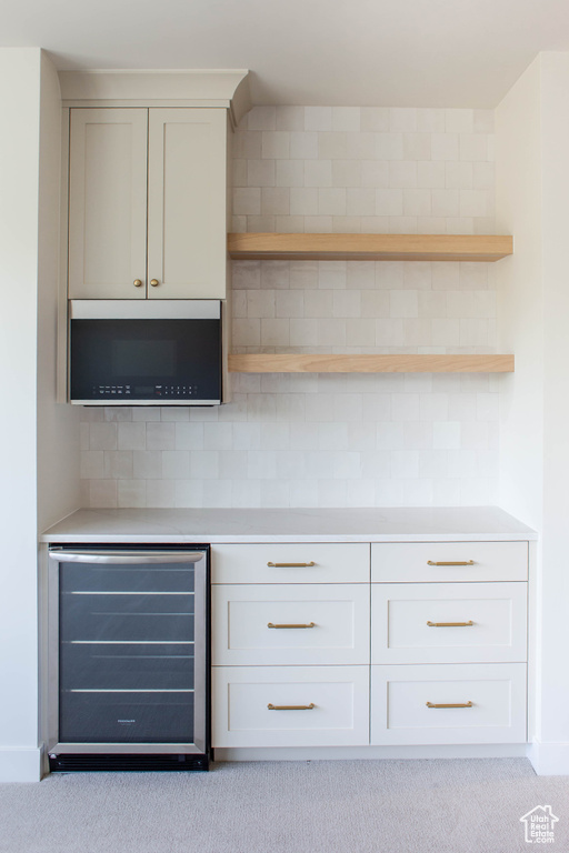 Indoor dry bar featuring beverage cooler, decorative backsplash, and carpet floors