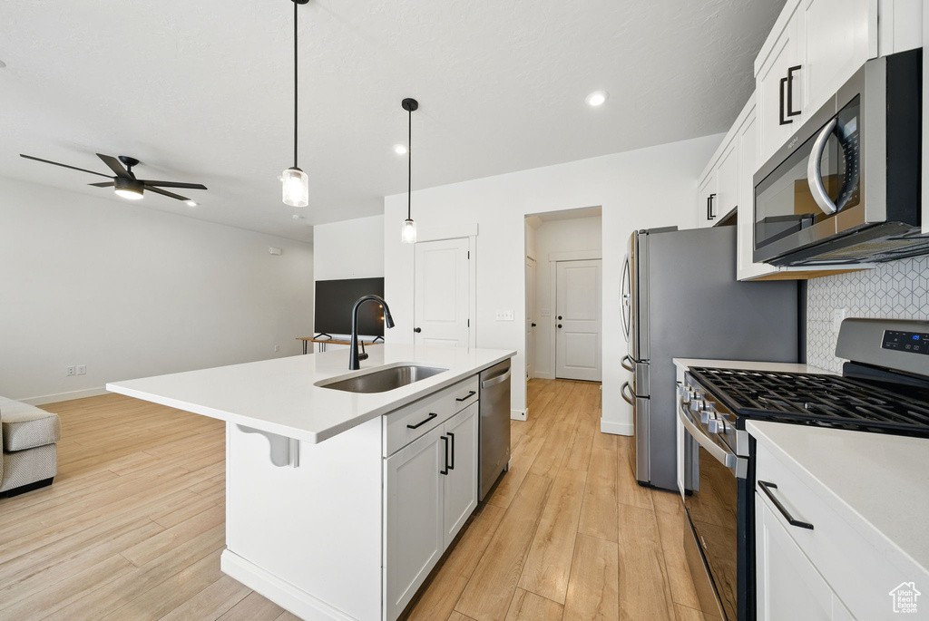 Kitchen featuring stainless steel appliances, a sink, open floor plan, backsplash, and recessed lighting