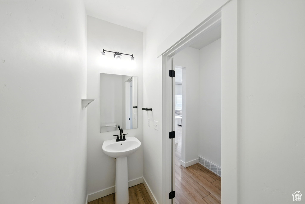 Bathroom with wood finished floors, a sink, and baseboards
