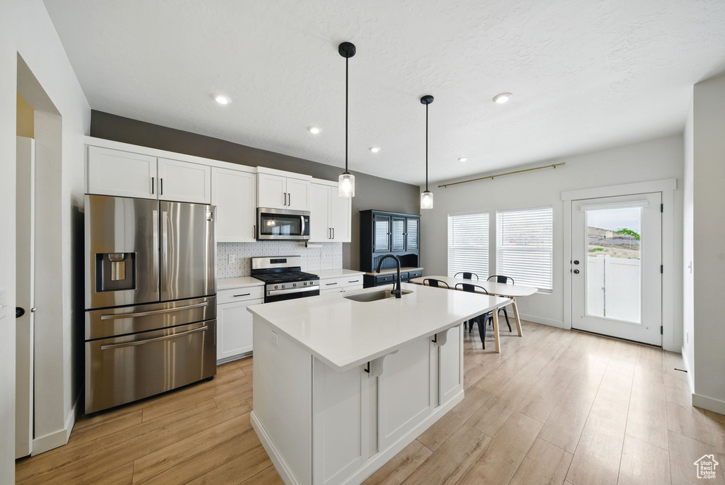 Kitchen featuring appliances with stainless steel finishes, a sink, white cabinets, and recessed lighting