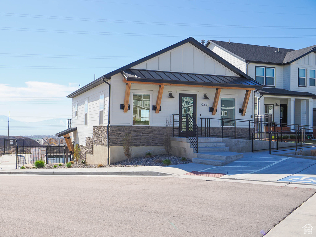 View of front of house with a standing seam roof, fence, stone siding, metal roof, and board and batten siding