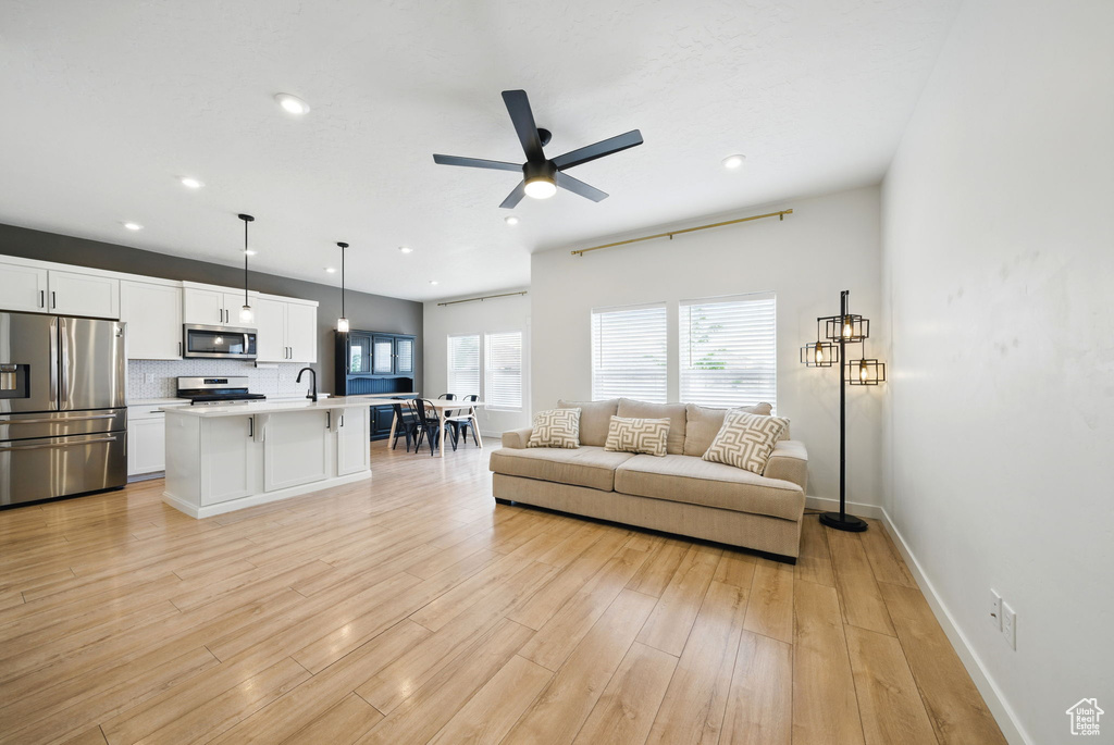 Living area with plenty of natural light, a ceiling fan, recessed lighting, light wood-type flooring, and baseboards