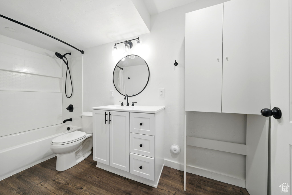 Full bathroom featuring wood finished floors, toilet, vanity, and tub / shower combination