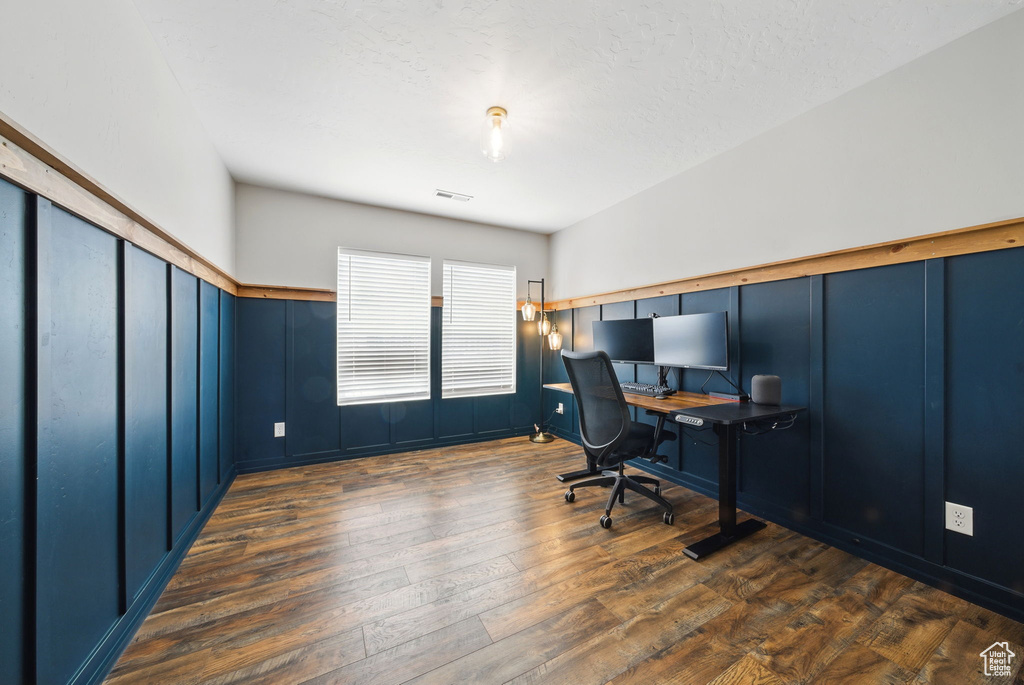Office featuring dark wood finished floors, a decorative wall, and wainscoting