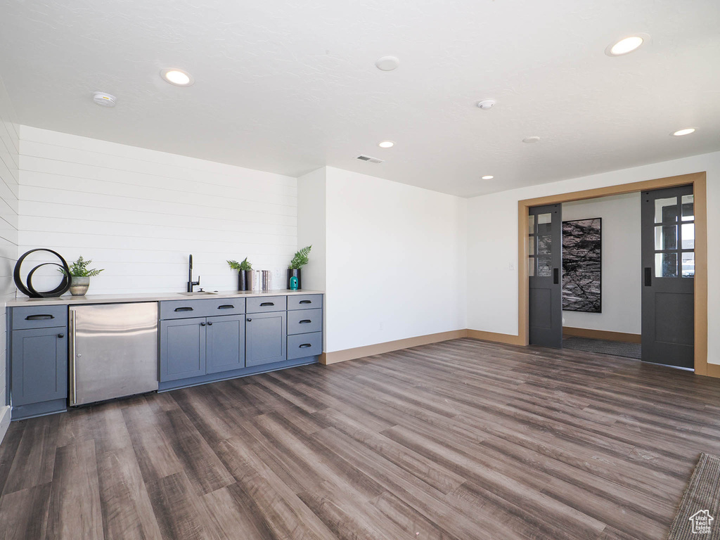 Kitchen with stainless steel refrigerator, dark wood finished floors, light countertops, recessed lighting, and a sink