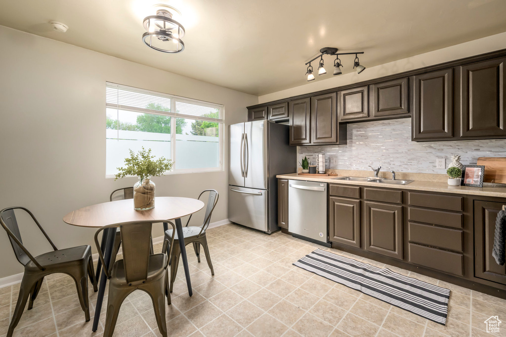 Kitchen featuring appliances with stainless steel finishes, a sink, light countertops, and dark brown cabinets
