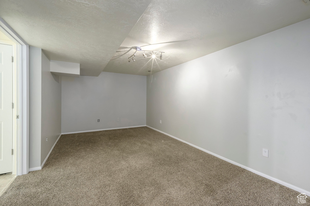 Unfurnished room featuring carpet, a textured ceiling, and baseboards