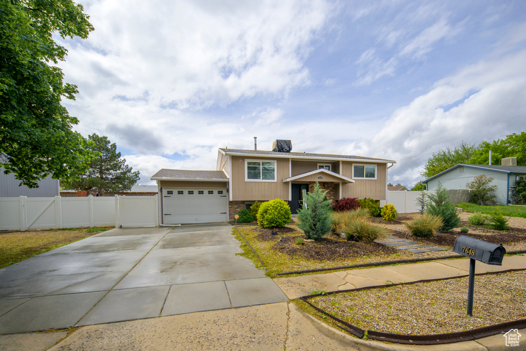 View of front of property with concrete driveway, a garage, fence, and a gate