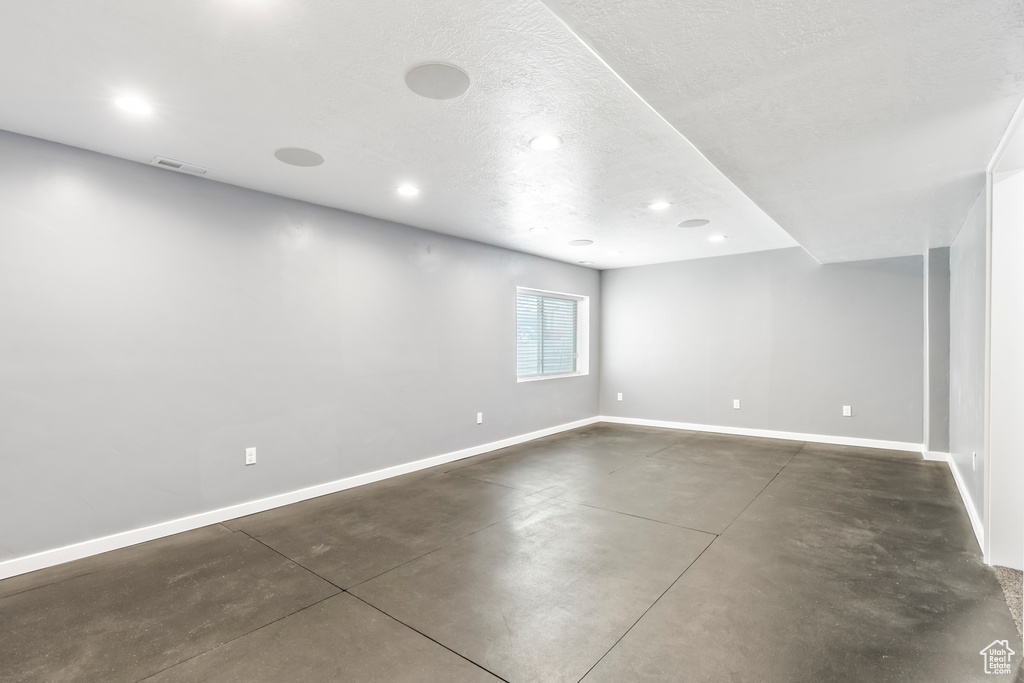 Unfurnished room featuring finished concrete floors, baseboards, recessed lighting, and a textured ceiling