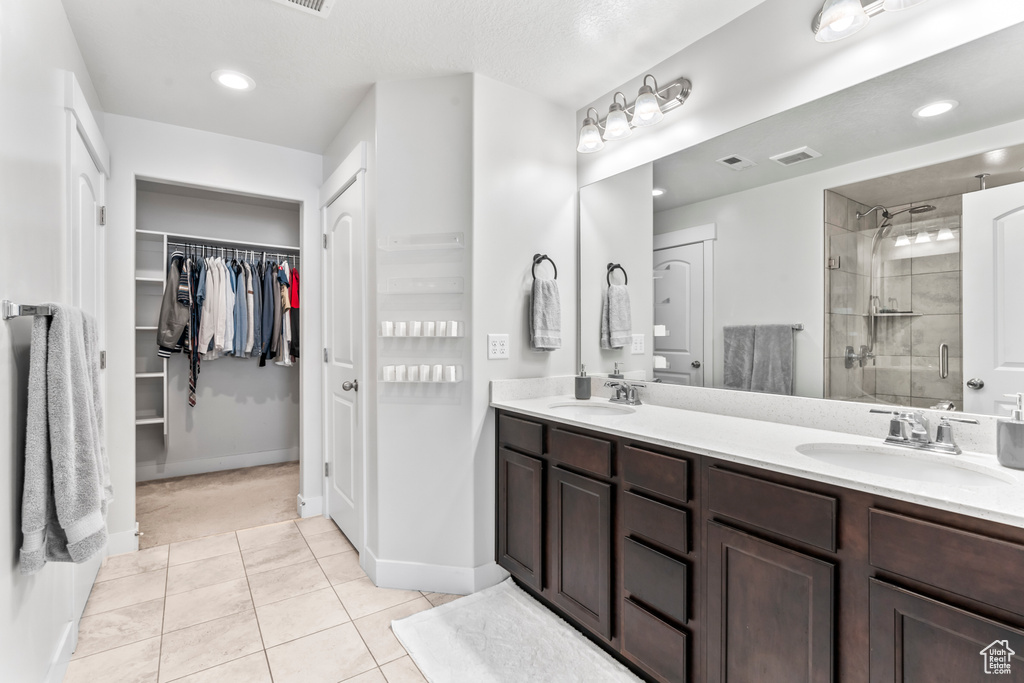 Full bathroom featuring a stall shower, double vanity, tile patterned flooring, a spacious closet, and recessed lighting