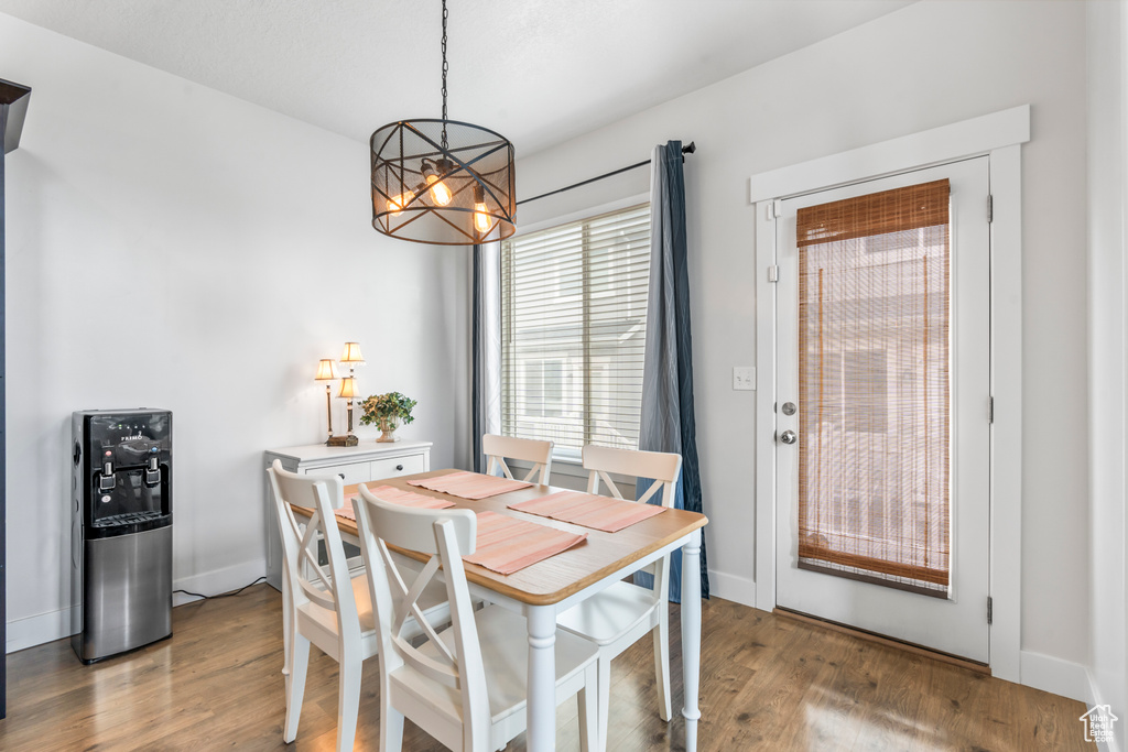 Dining area with a chandelier, wood finished floors, and baseboards