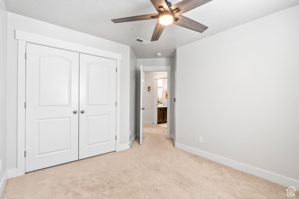 Unfurnished bedroom with light carpet, baseboards, a closet, and ceiling fan