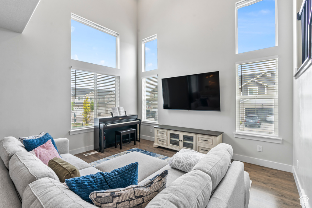 Living area featuring baseboards, a towering ceiling, and wood finished floors