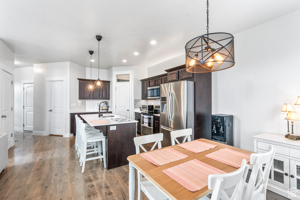 Dining room with a chandelier, wood finished floors, and recessed lighting