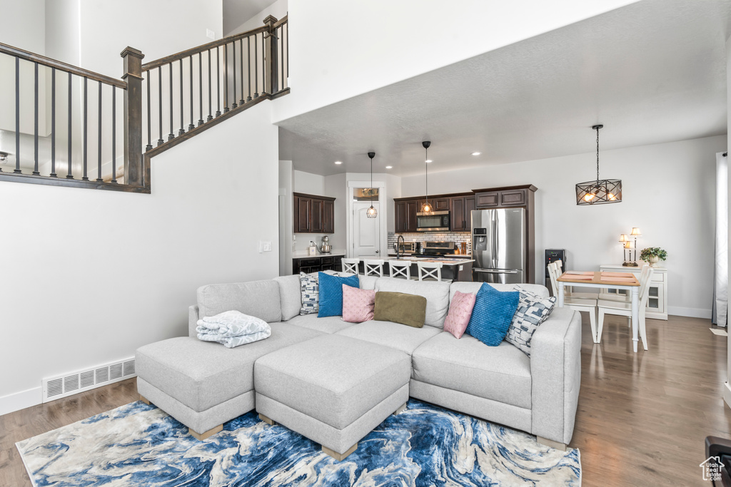Living area with wood finished floors, a chandelier, baseboards, and recessed lighting