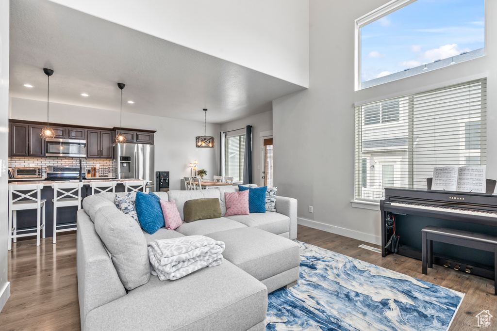 Living area with wood finished floors, plenty of natural light, baseboards, recessed lighting, and a high ceiling