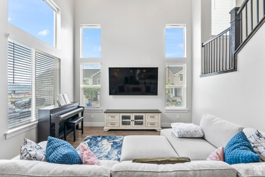 Living room with a high ceiling, wood finished floors, and baseboards
