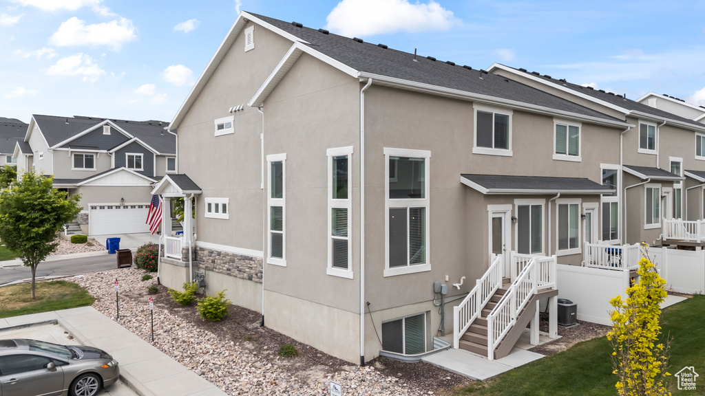 View of front facade featuring stucco siding, a residential view, and central AC
