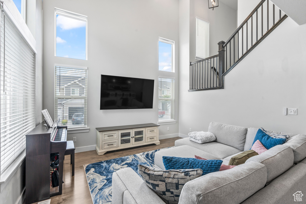 Living room with a towering ceiling, plenty of natural light, wood finished floors, and baseboards