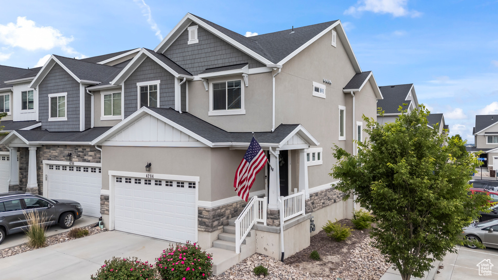 View of front of property featuring stone siding, a garage, driveway, and stucco siding