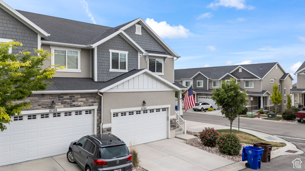View of front of property featuring concrete driveway, a garage, a residential view, and stucco siding