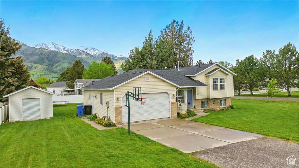 Split level home featuring a front yard, a mountain view, driveway, brick siding, and a storage unit