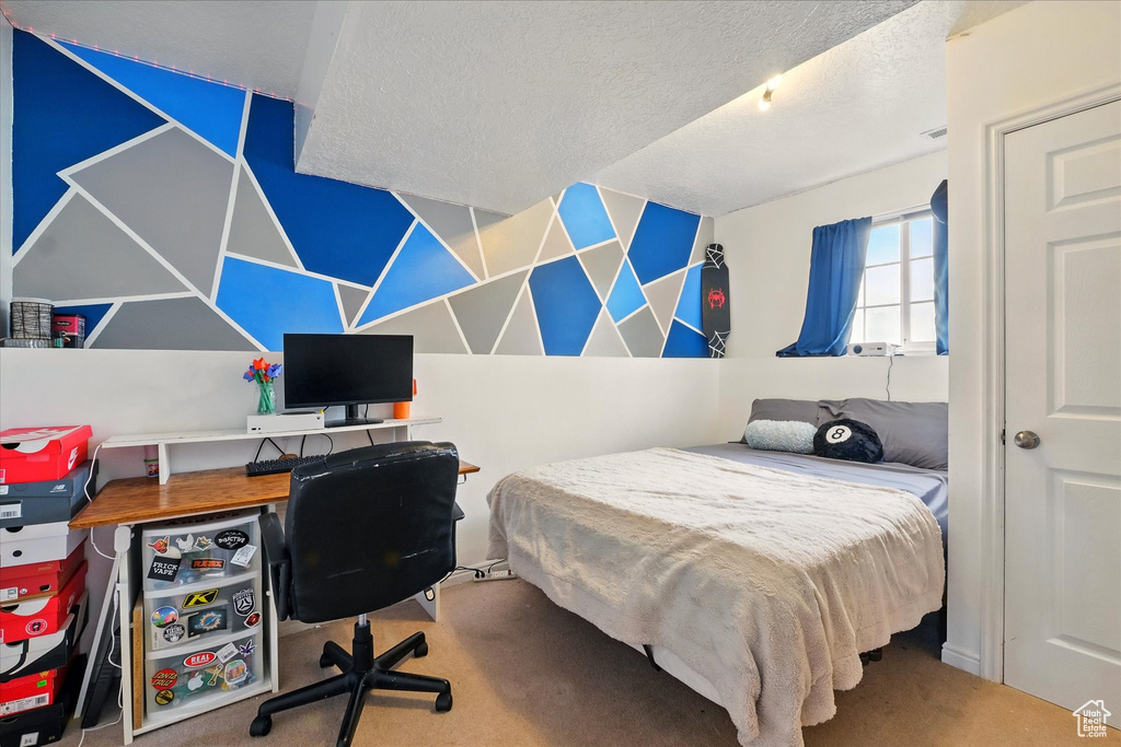 Carpeted bedroom with an office area and a textured ceiling