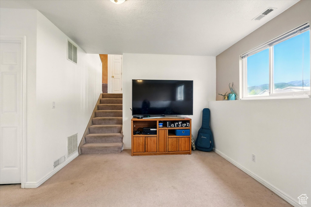 Carpeted living area with baseboards and stairs