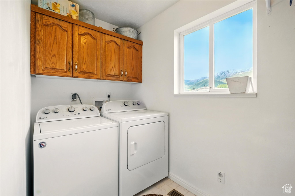 Clothes washing area featuring washer and dryer, cabinet space, and baseboards