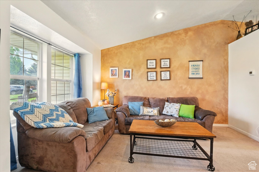 Living area with lofted ceiling, light colored carpet, and baseboards