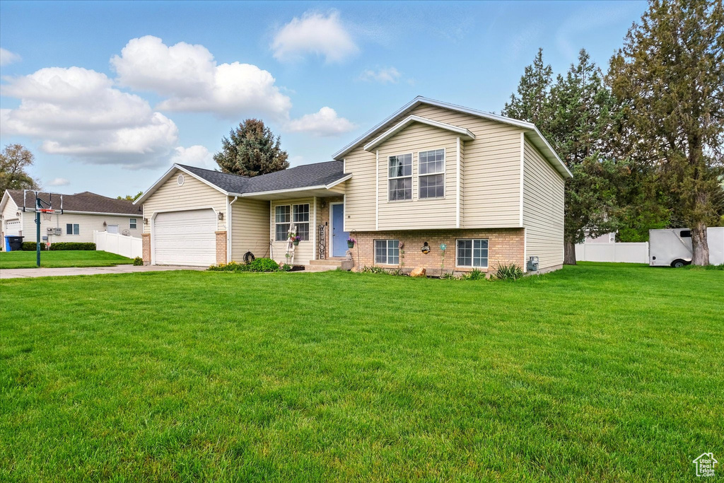 Tri-level home with concrete driveway, an attached garage, and brick siding