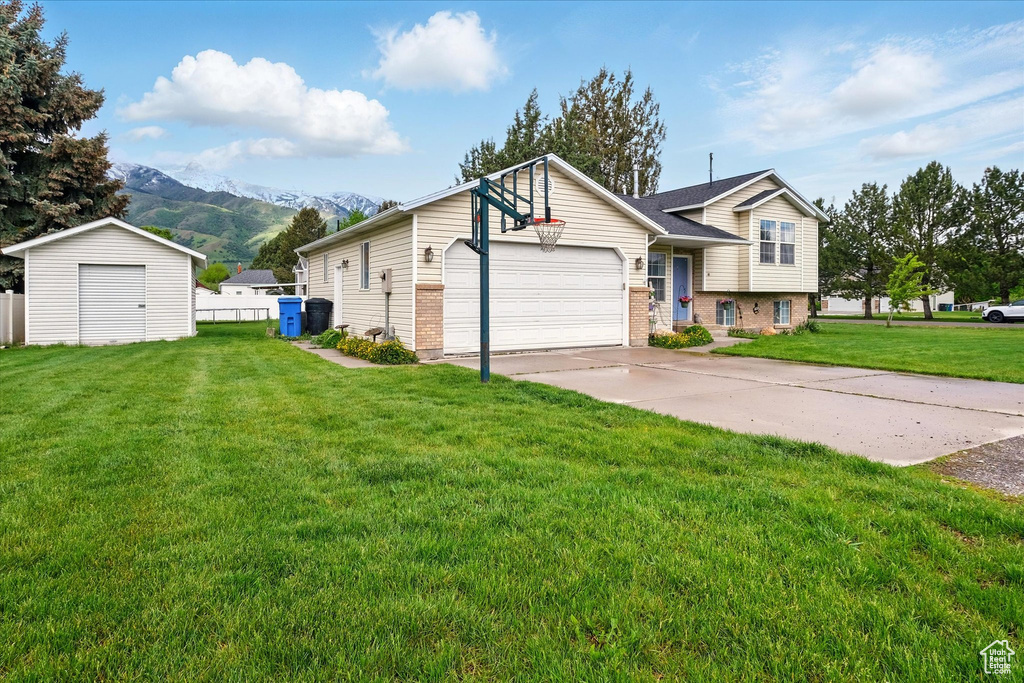 View of front of home featuring brick siding, a mountain view, a shed, driveway, and an outdoor structure