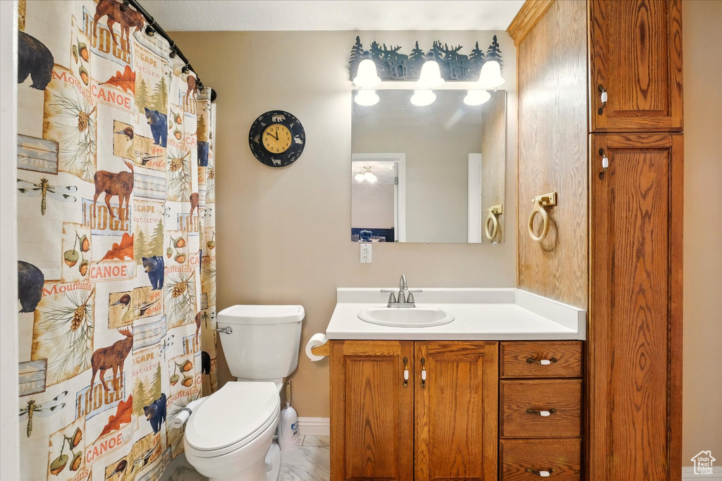 Full bathroom featuring toilet, vanity, curtained shower, and baseboards