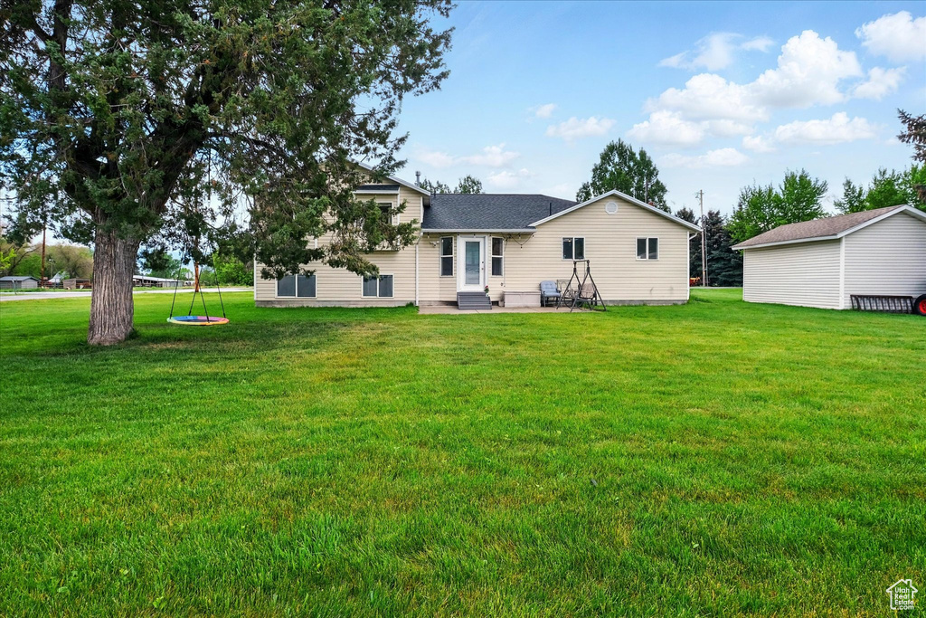 Rear view of house featuring a yard, a patio, roof with shingles, and entry steps