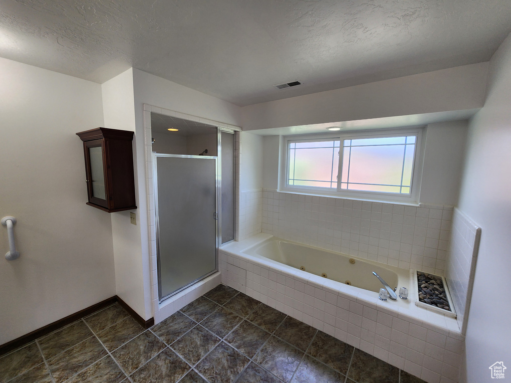 Bathroom featuring a stall shower, a whirlpool tub, a textured ceiling, tile patterned flooring, and baseboards