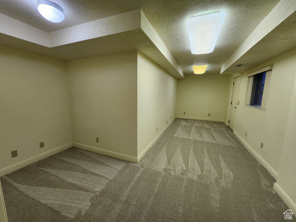 Finished basement featuring a textured ceiling, carpet floors, and baseboards
